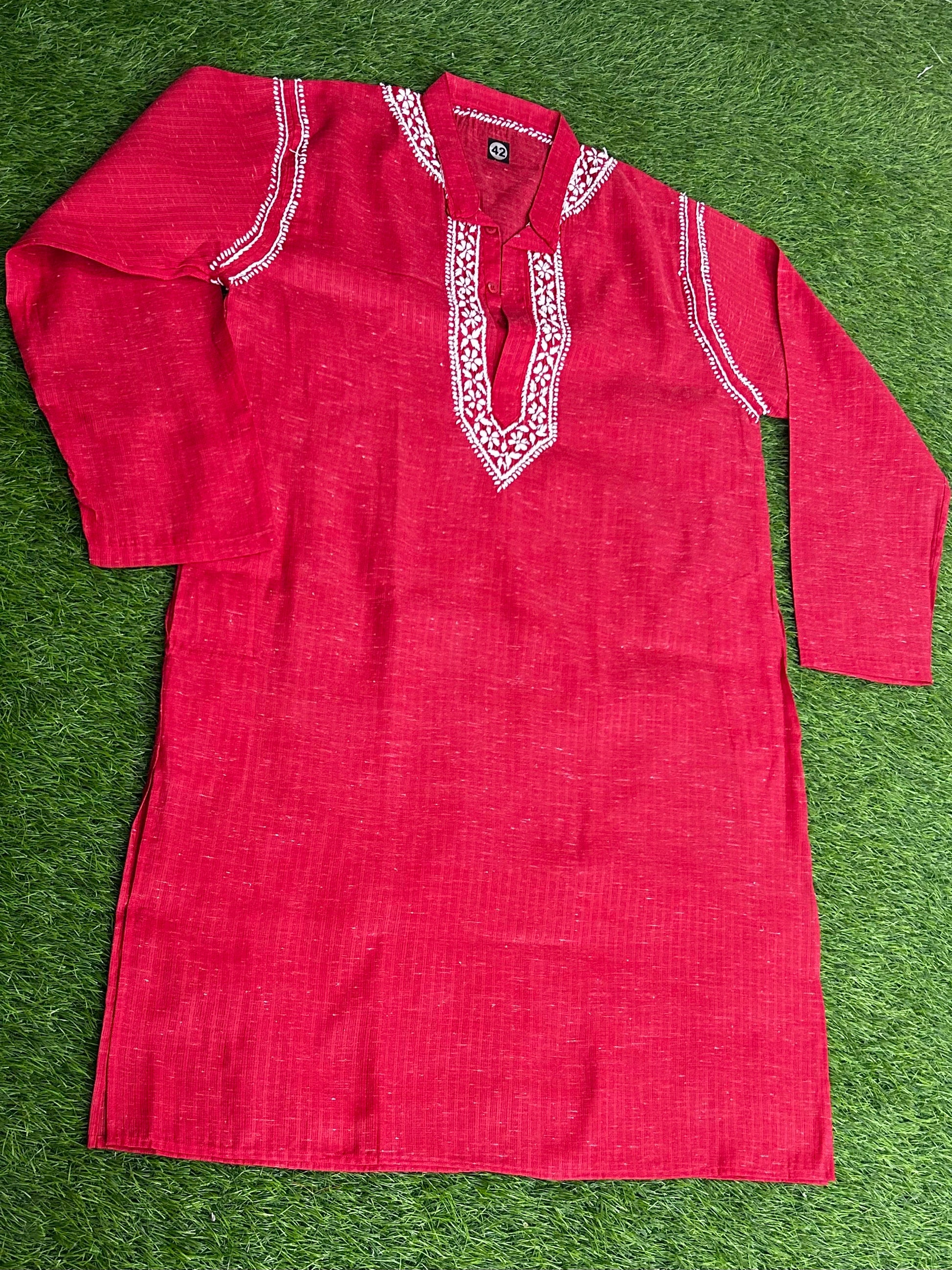 Red kurta with white embroidery on a green grass background