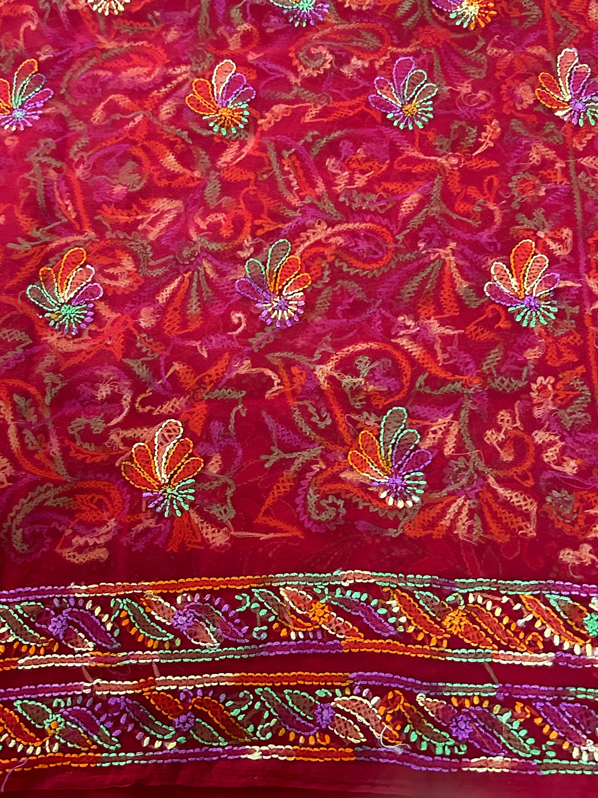 Embroidered fabric with colorful floral patterns on a red background