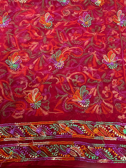 Embroidered fabric with colorful floral patterns on a red background