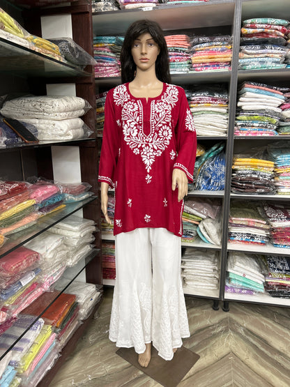 Mannequin wearing a red embroidered top and white pants in a fabric store.