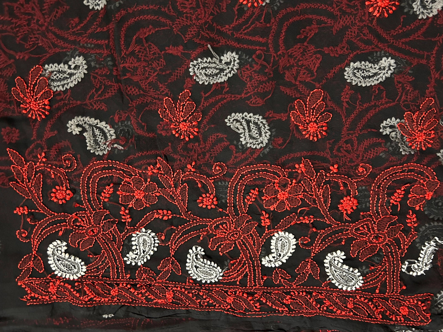 lucknowi chikankari Close-up of a black fabric with red and white floral embroidery