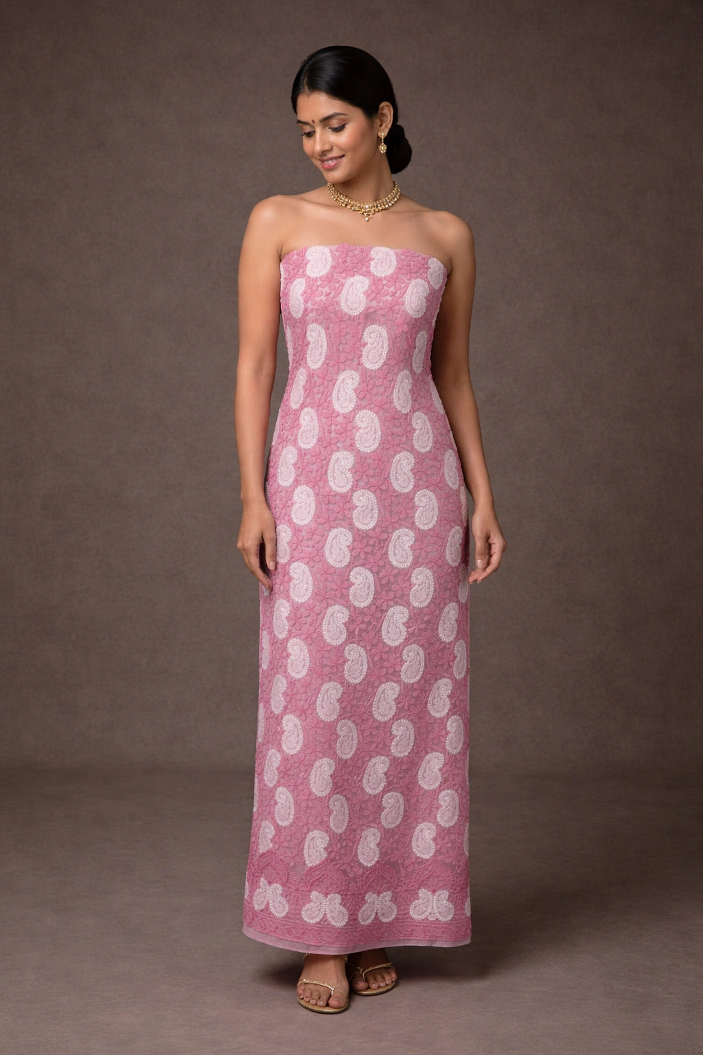 Woman wearing a lucknowi chikankari pink strapless dress with white patterns on a brown background