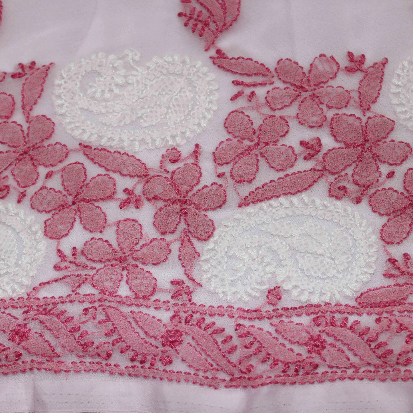 Close-up of pink floral embroidery on a white fabric background