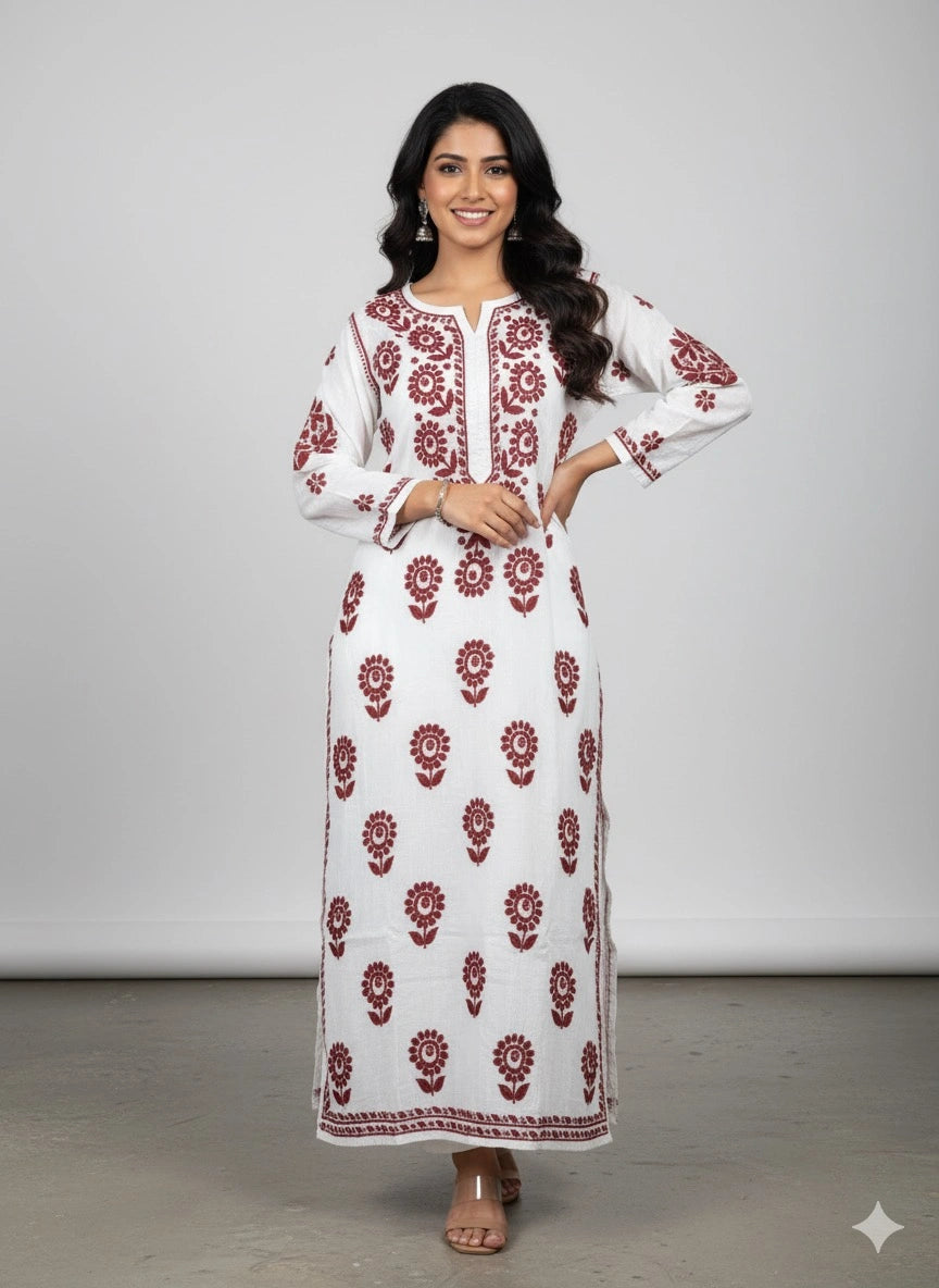Woman wearing a lucknowi chikankari white dress with red floral patterns against a plain background