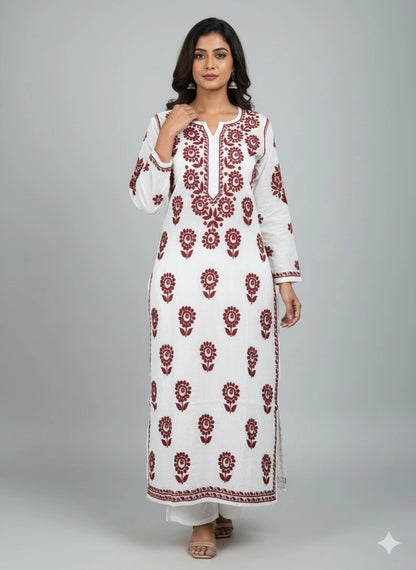 Woman wearing a lucknowi chikankari white dress with red floral patterns on a gray background