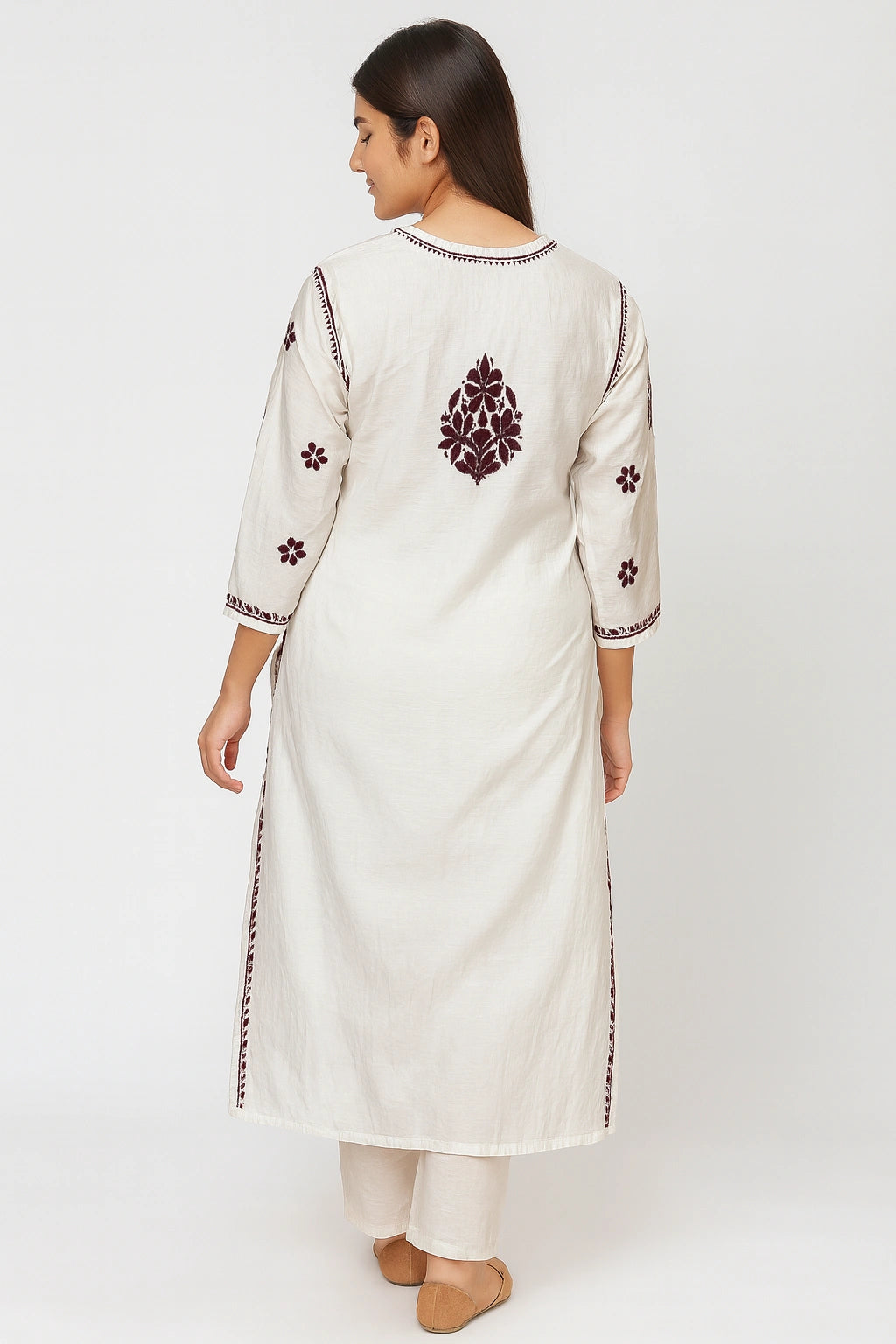 Woman wearing a white kurta with intricate embroidery on a white background