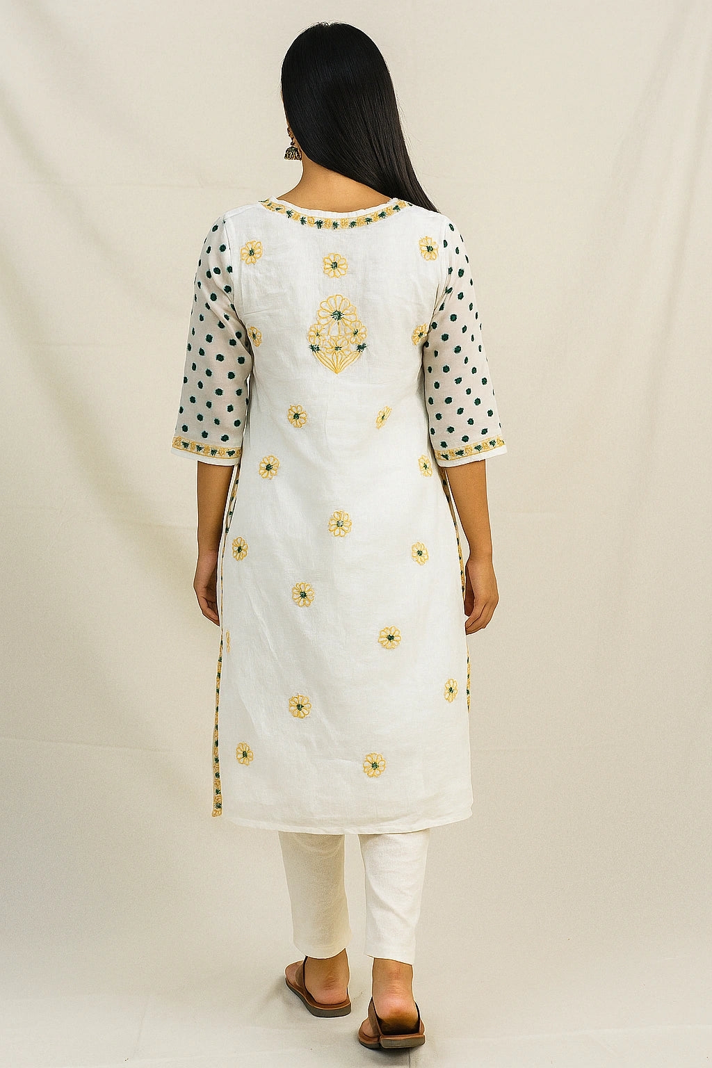Woman wearing a lucknowi chikankari white kurta with yellow floral embroidery on a plain background
