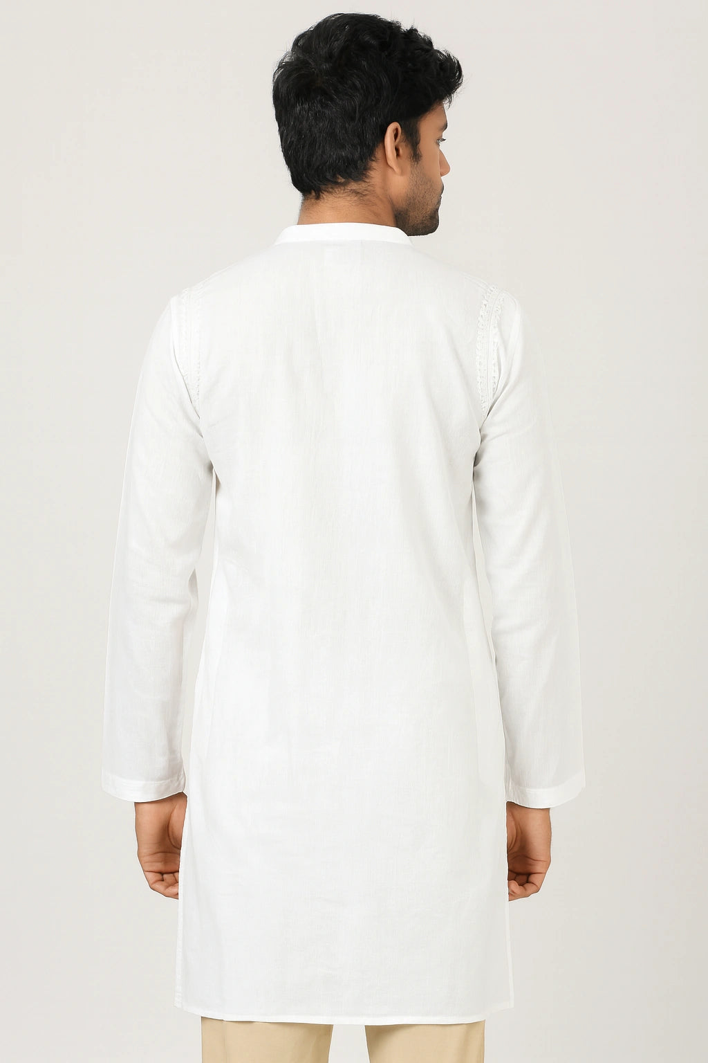 Man wearing a lucknowi chikankari white kurta with beige pants on a light gray background