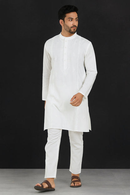 Man wearing a lucknowi chikankari white kurta with white pants against a black background