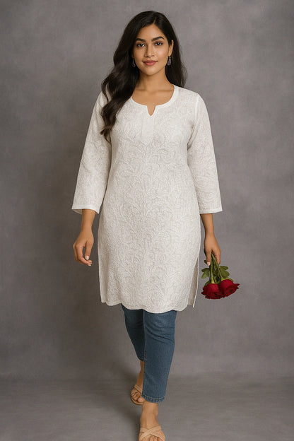 Woman wearing a lucknowi chikankari light gray kurta with blue jeans, holding red roses against a gray background