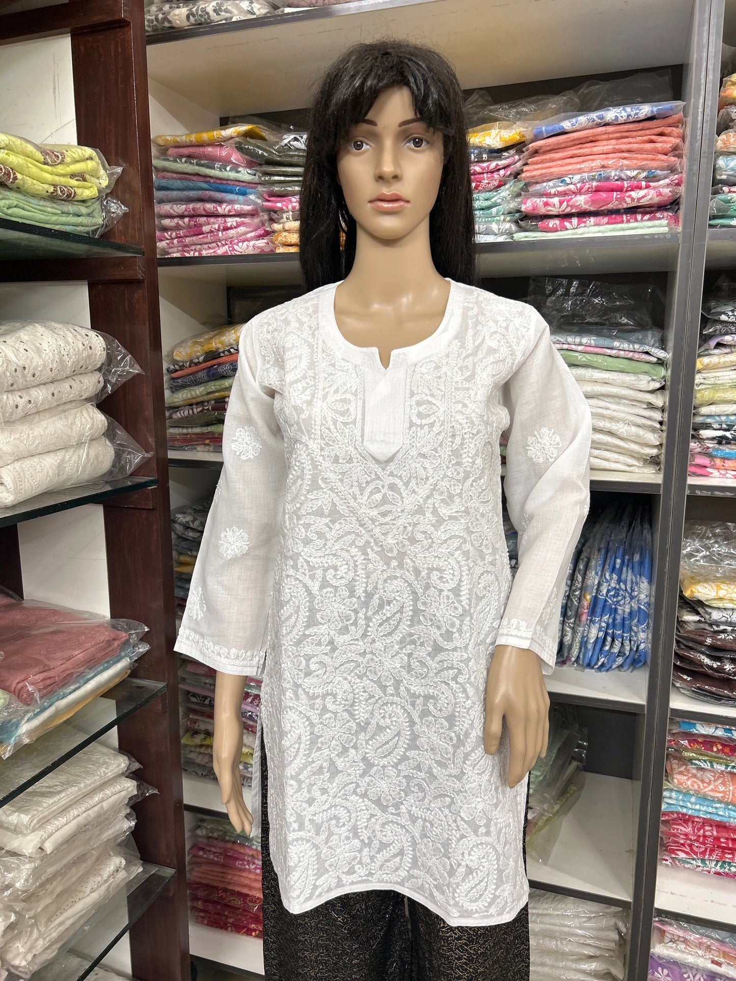 Mannequin wearing a white embroidered top in a fabric store
