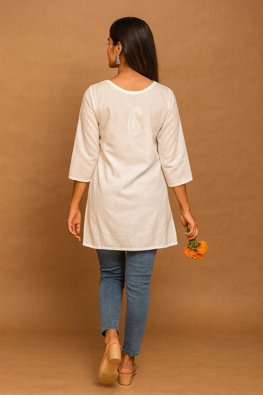 lucknowi chikankari Woman wearing a beige tunic and blue jeans against a brown background