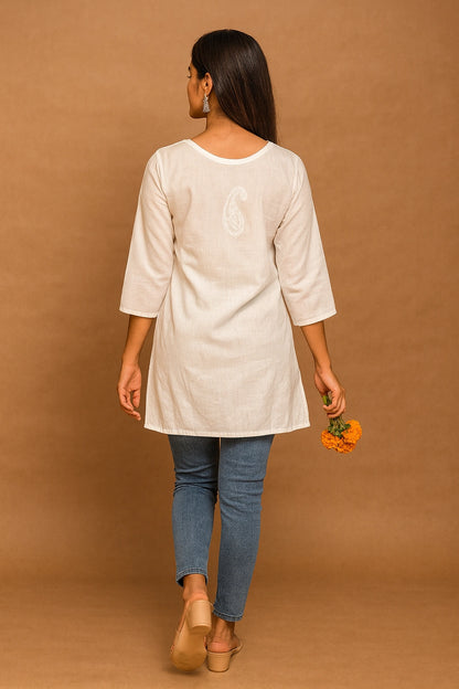 lucknowi chikankari Woman wearing a beige tunic and blue jeans against a brown background