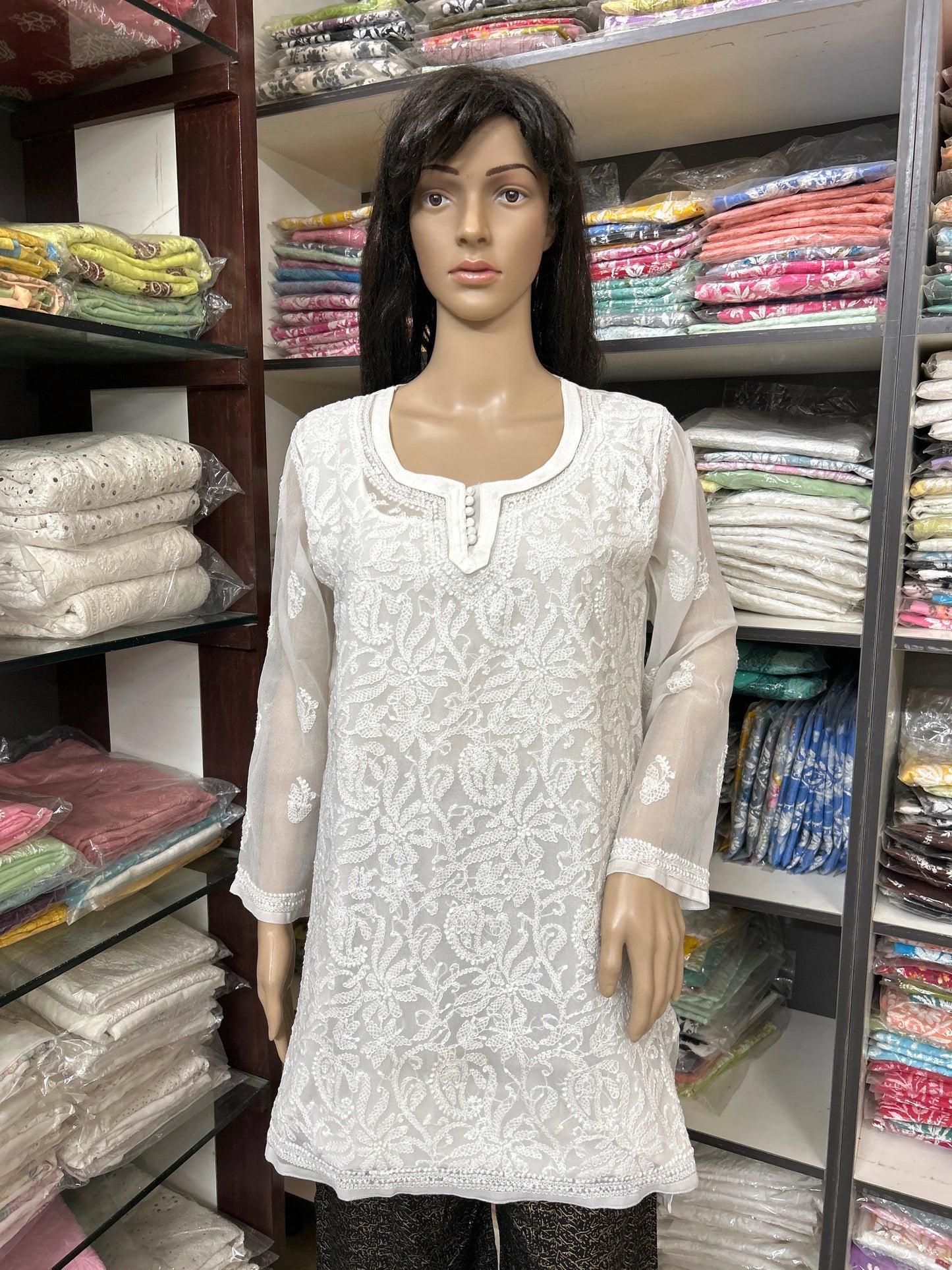 Mannequin wearing a white embroidered kurta in a fabric store.