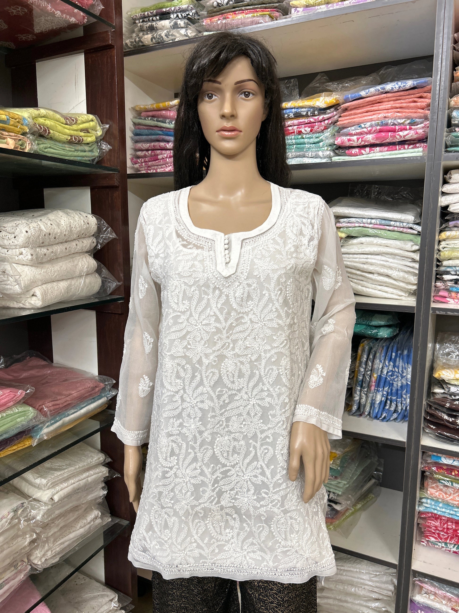 Mannequin wearing a white embroidered kurta in a fabric store.
