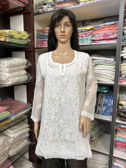 Mannequin wearing a white embroidered kurta in a fabric store.