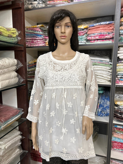 Mannequin wearing a white embroidered dress in a fabric store.