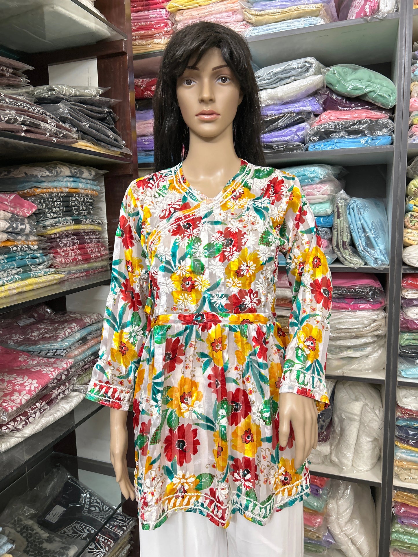 lucknowi chikankari Mannequin wearing a colorful floral blouse in a fabric store.