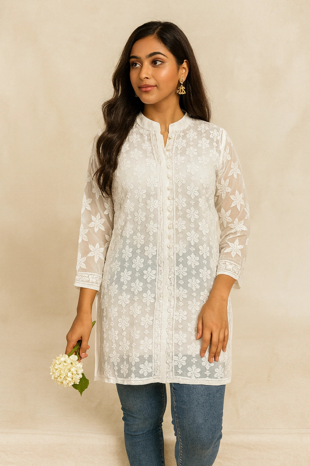 Woman wearing a lucknowi chikankari white floral lace top with blue jeans against a beige background