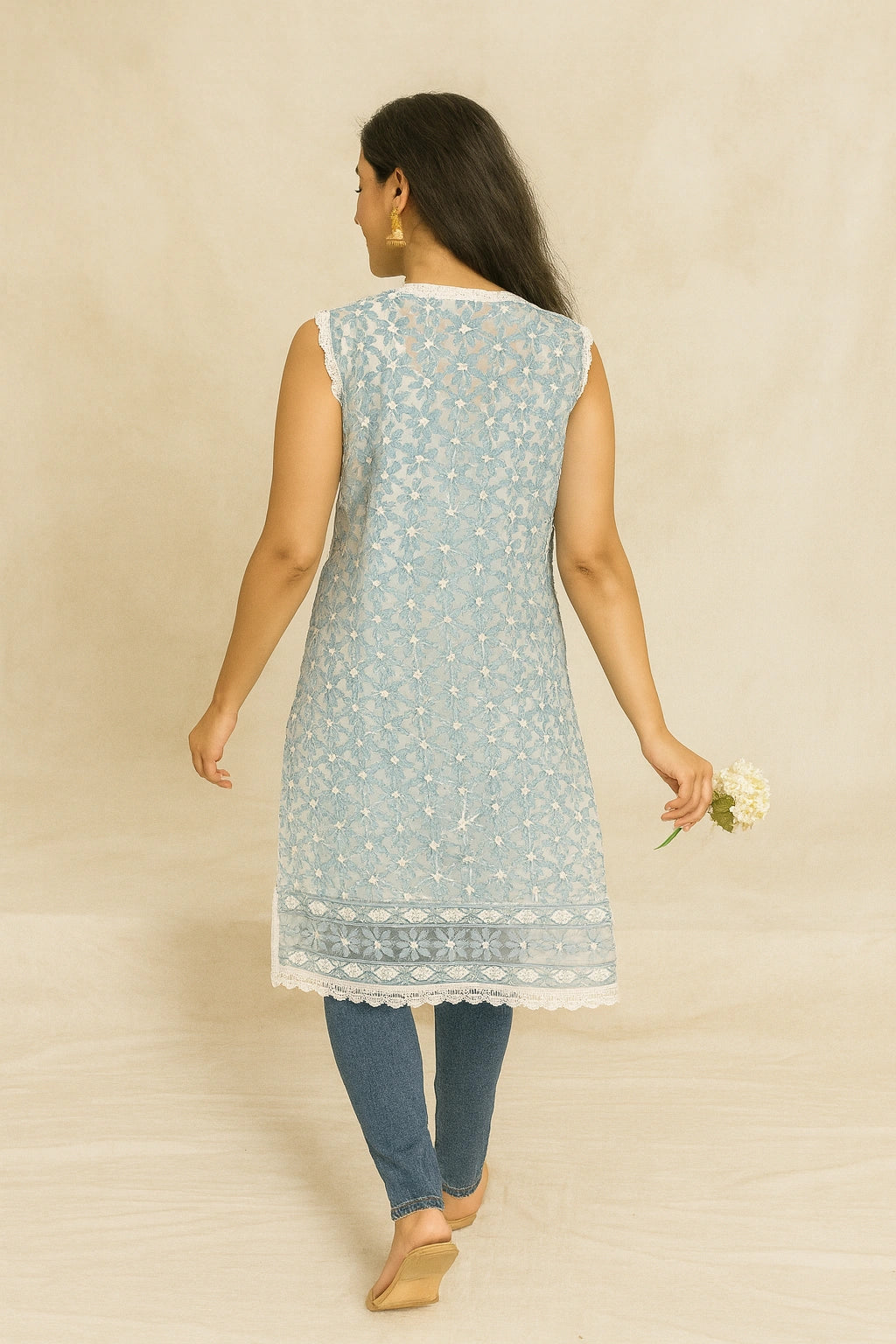 Woman wearing a lucknowi chikankari light blue sleeveless kurta with white patterns on a beige background