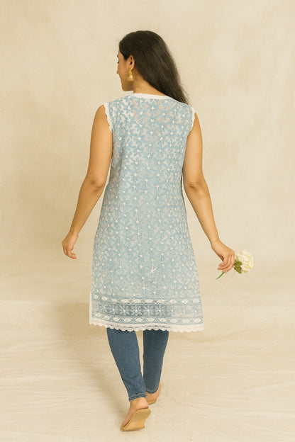 Woman wearing a lucknowi chikankari light blue sleeveless kurta with white patterns on a beige background