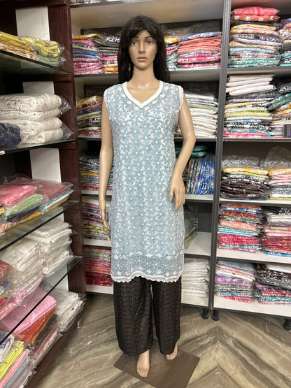 Mannequin wearing a lucknowi chikankari light blue patterned dress with dark pants in a fabric store.