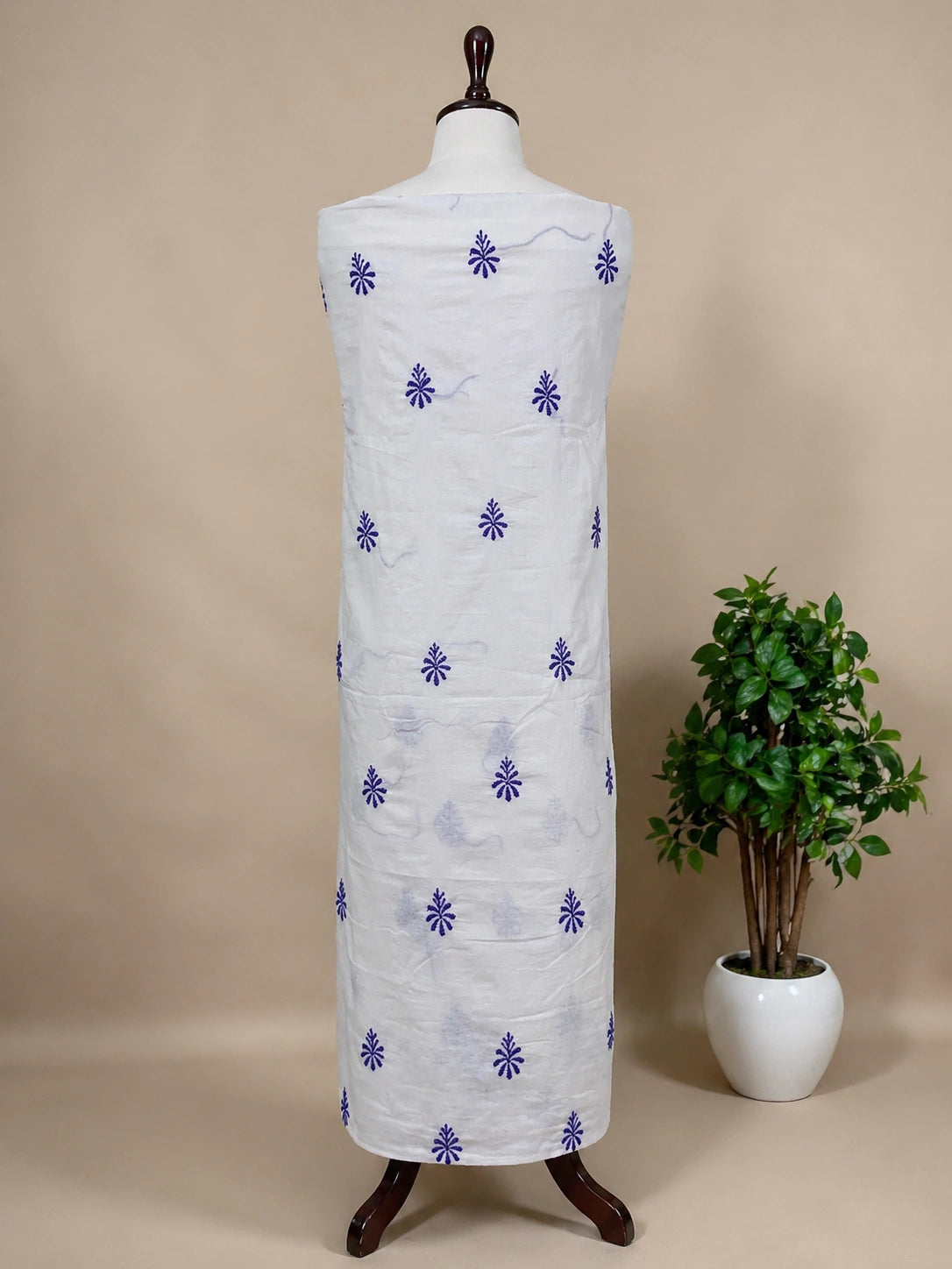 Mannequin wearing a white garment with purple floral patterns against a beige background