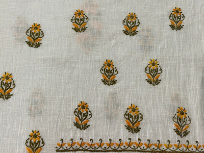 White fabric with floral embroidery in orange and green