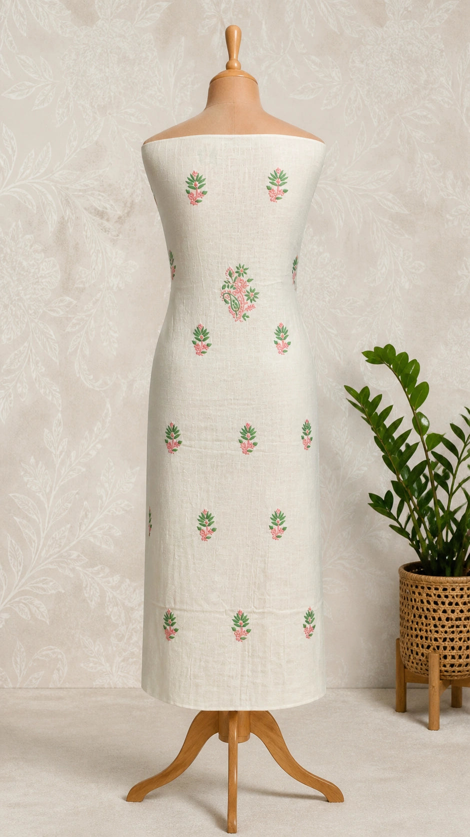 Lucknowi chikankari white dress with floral patterns on a mannequin against a gray wall with decorative panels.
