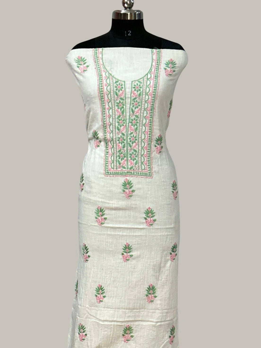 White embroidered dress on a mannequin against a gray background