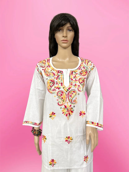 White embroidered dress with colorful patterns on a pink background