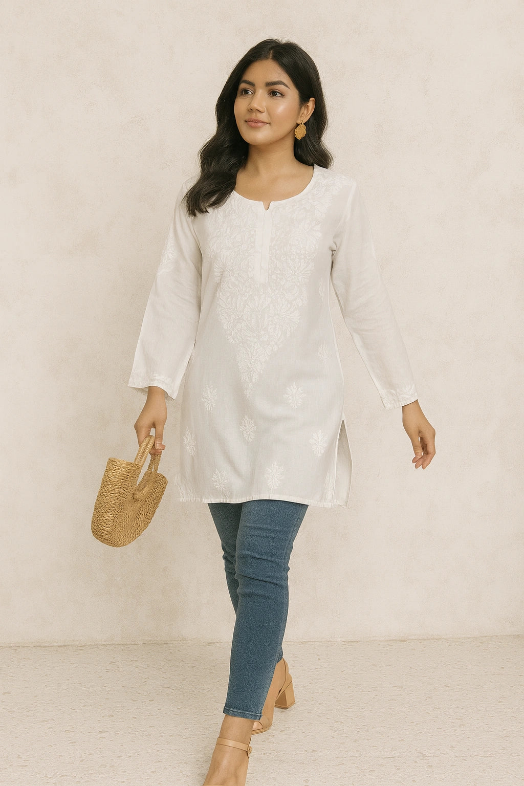 lucknowi chikankari Woman wearing a white long-sleeve top and blue jeans, holding a woven handbag against a plain background