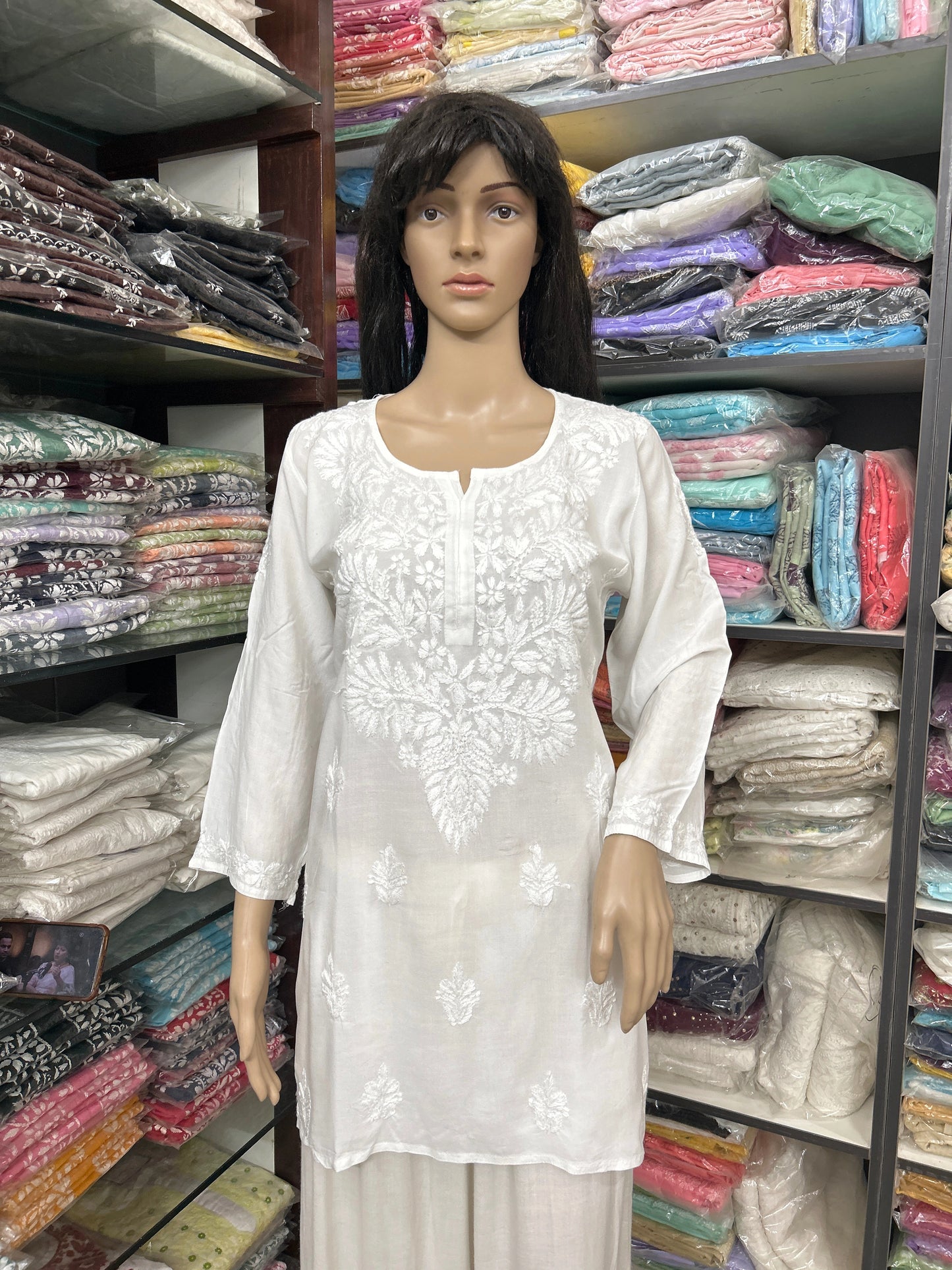 Mannequin wearing a white embroidered top in a fabric store