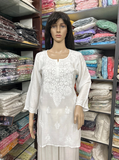 Mannequin wearing a white embroidered top in a fabric store