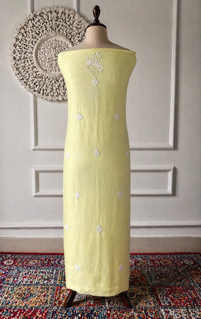 Light green dress with silver embroidery on a mannequin against a decorative wall.