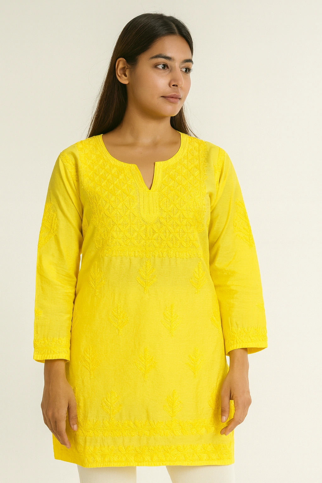 Woman wearing a lucknowi chikankari yellow kurta against a plain background