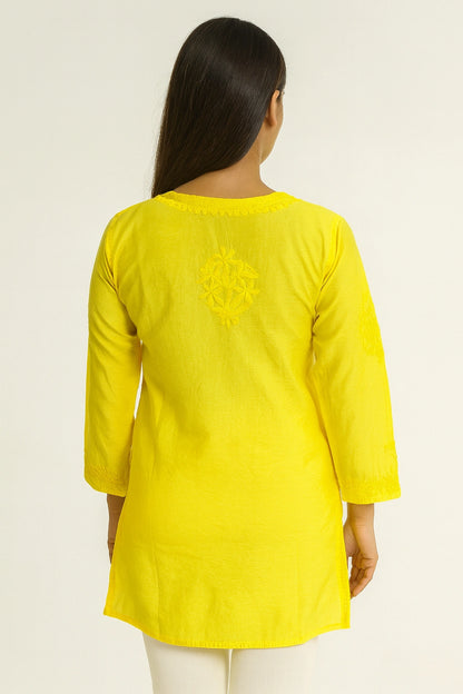 Woman wearing a lucknowi chikankari yellow kurta with intricate design on a white background