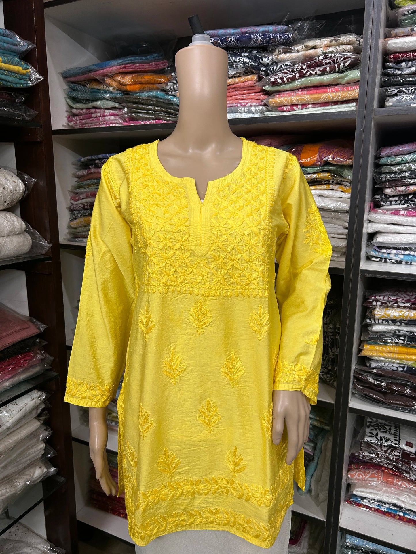 Yellow embroidered kurta on a mannequin in a fabric store