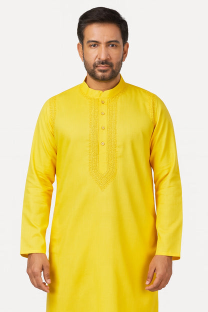 Man wearing a lucknowi chikankari  yellow kurta against a white background