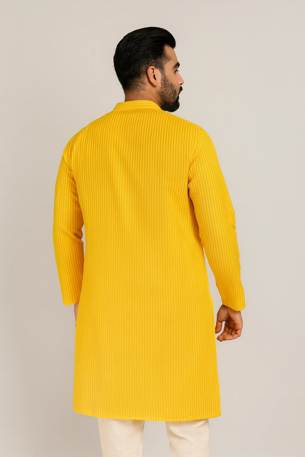 Man wearing a lucknowi chikankari yellow kurta against a plain background