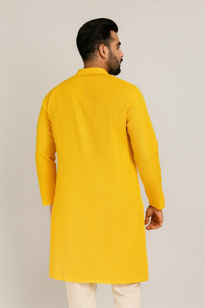 Man wearing a lucknowi chikankari yellow kurta against a plain background