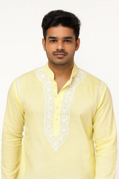 Man wearing a light yellow kurta with white embroidery on a white background