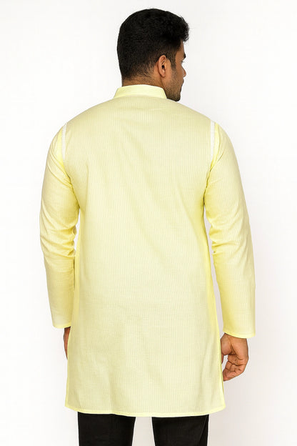 Man wearing a lucknowi chikankari light yellow kurta with black pants on a white background