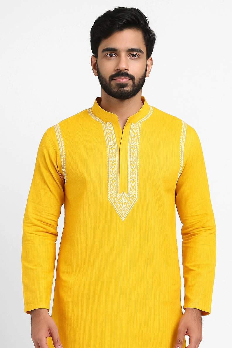 Man wearing a yellow kurta with white embroidery on a white background