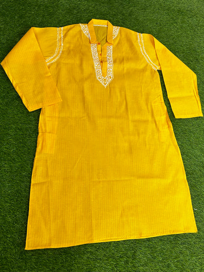 Yellow kurta with white embroidery on a green surface