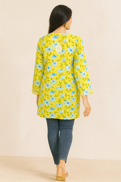 Woman wearing a lucknowi chikankari yellow floral dress with blue flowers on a beige background