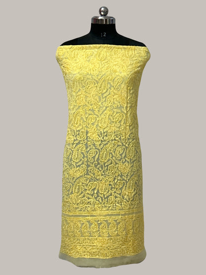 Yellow embroidered fabric on a mannequin against a gray background