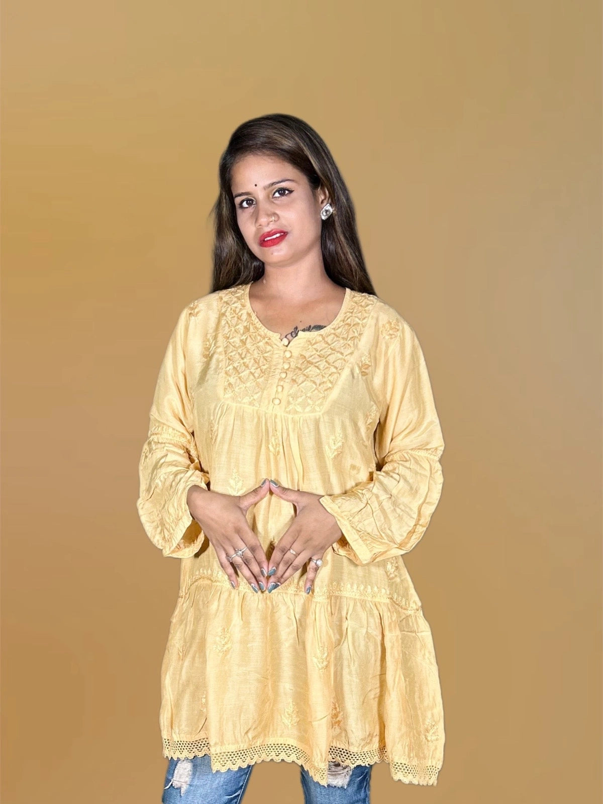 Woman wearing a lucknowi chikankari yellow lace top against a beige background