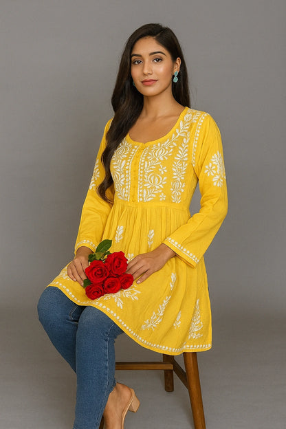Woman wearing a yellow embroidered dress holding red flowers against a gray background