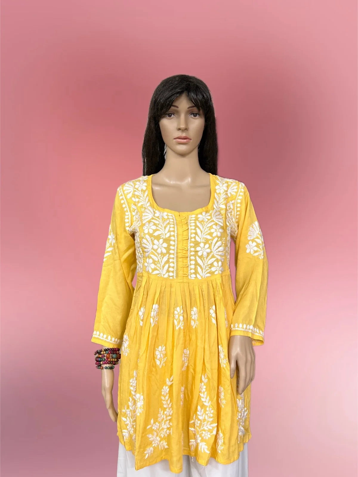 Yellow embroidered kurta on a mannequin against a pink gradient background